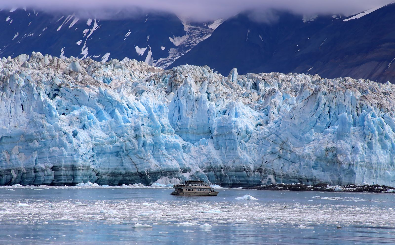 Small boat dwarfed by the ice face of Hubbard Glacier in Alaska, a highlight of domestic cruises in the USA